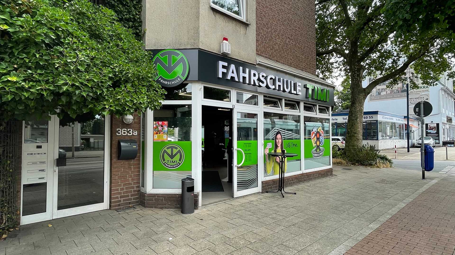 Eine Fahrschule mit grünem und weißem Logo und großen Fensterscheiben.