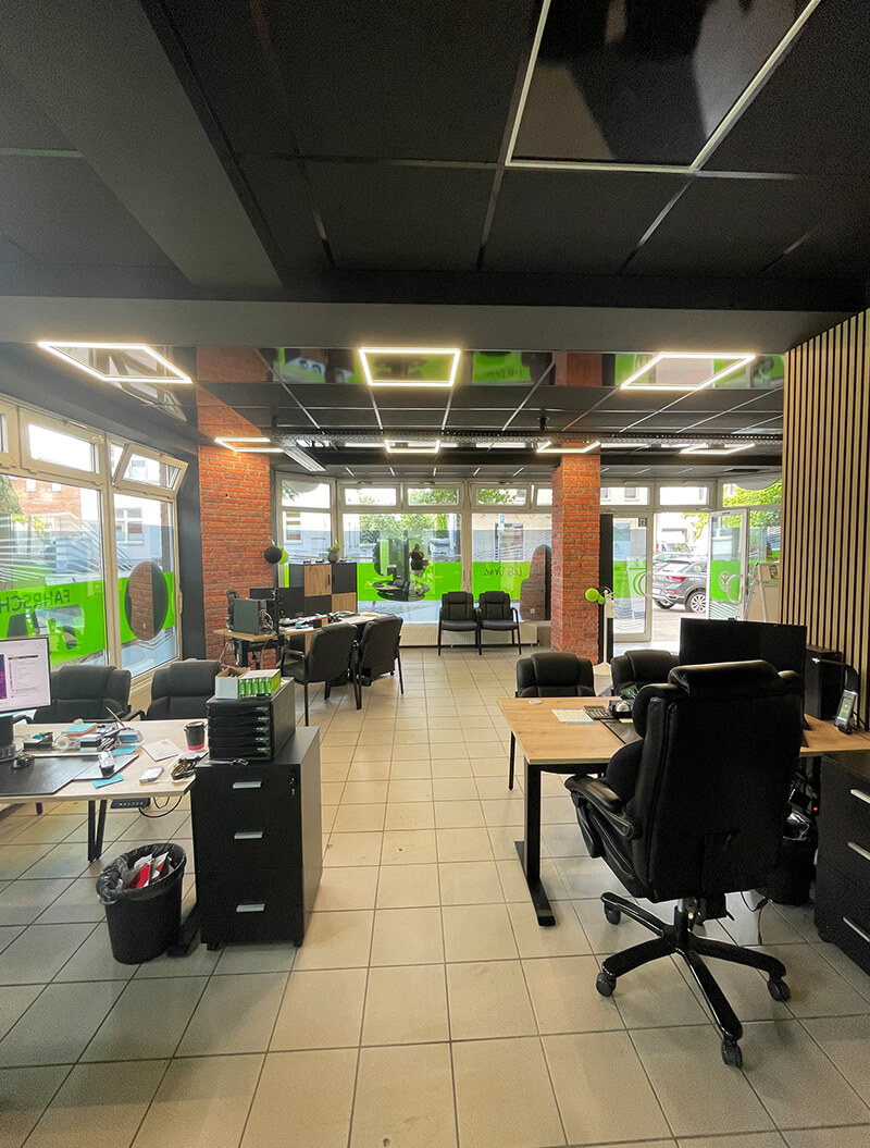 Modernes Büro mit schwarzen Decken, Holzmöbeln und leuchtend grünen Akzenten