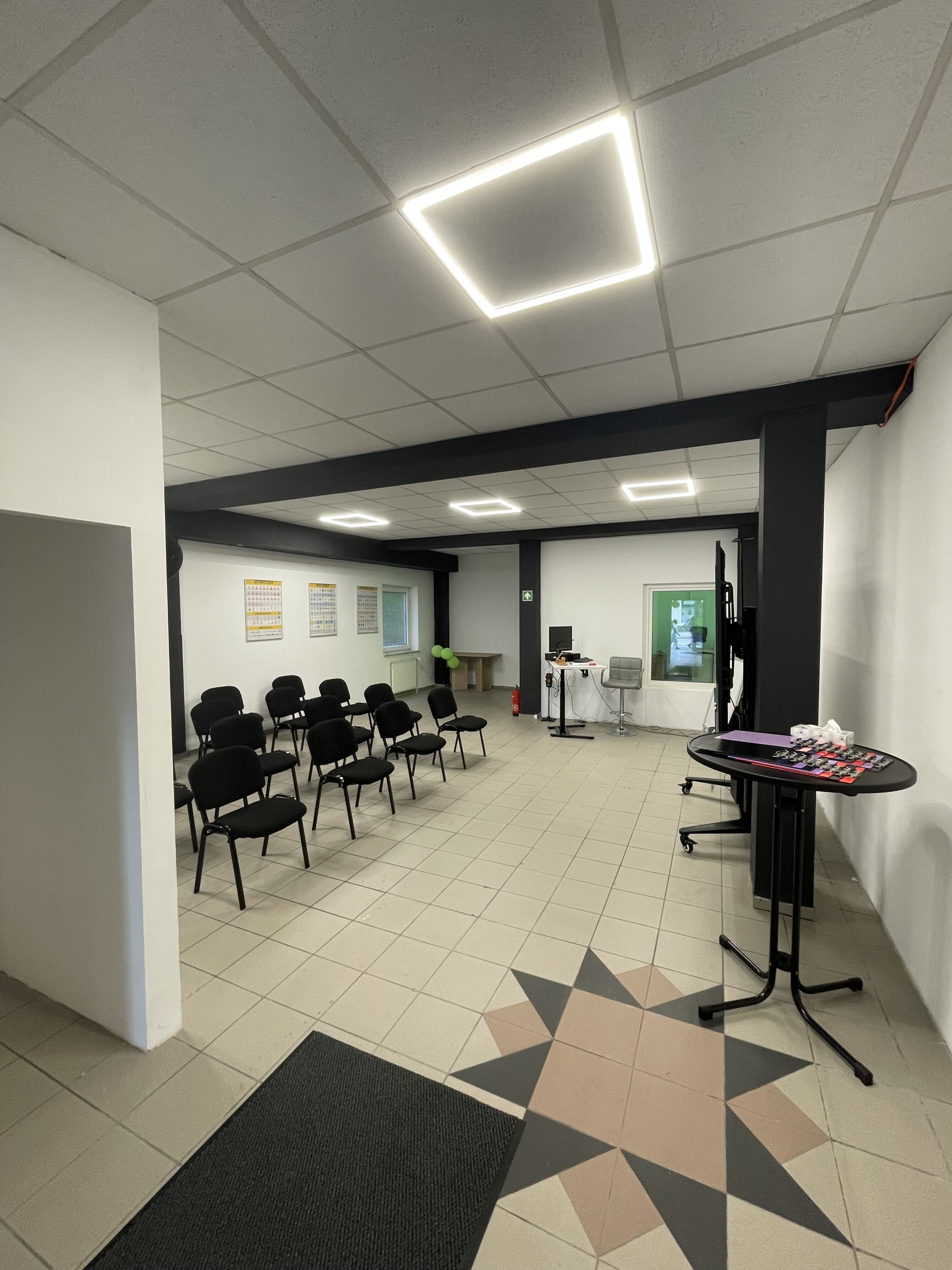 Ein heller Besprechungsraum mit Stühlen, Tisch und Infotafeln an den Wänden