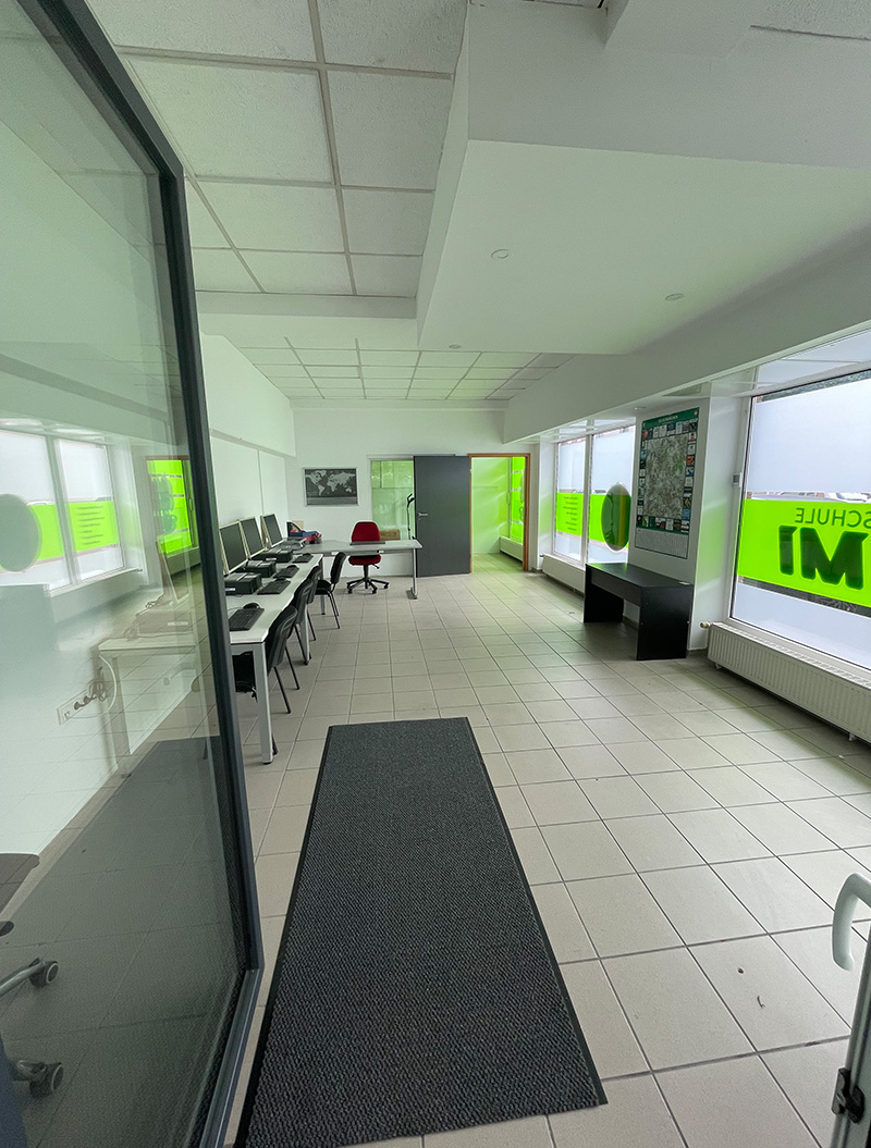 Ein leerer Büroraum mit Reihen von Computern und leuchtend grünen Wänden