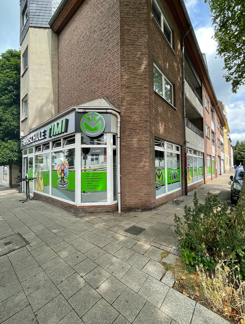 Eine Fahrschule mit grüner und weißer Fassade an einer Straßenecke.