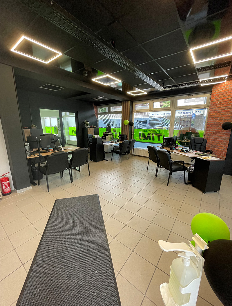 Ein modernes Büro mit sechs leeren schwarzen Stühlen und großen Fenstern.